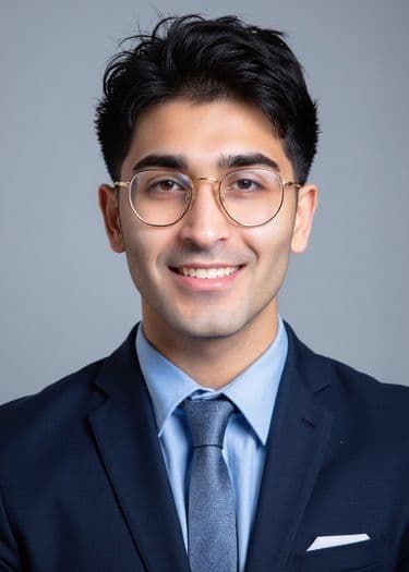 Example ERAS headshot — man in navy suit and tie with glasses on gray background.